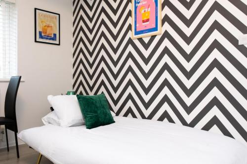 a white bed in a room with a chevron wall at Modern flat - Sleeps 3 - London in Enfield