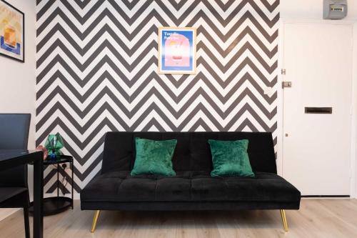 un sofá negro con 2 almohadas verdes en la sala de estar en Modern flat - Sleeps 3 - London, en Enfield