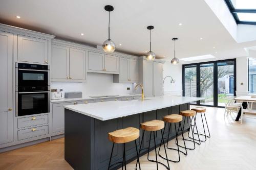 a kitchen with white cabinets and a island with bar stools at Veeve - The Peace Lily in London
