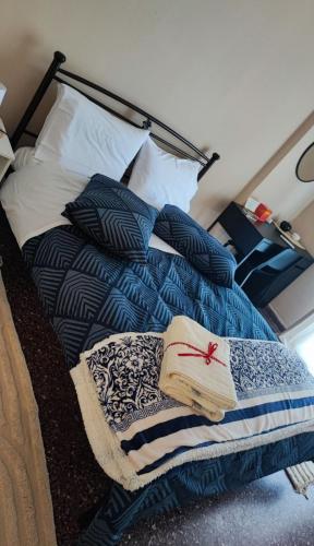 a bed with blue and white sheets and a book at Sea side apartment in Loutraki