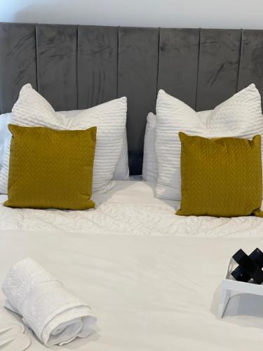 Luxury en-suite in modern house في Catford: سرير عليه وسائد بيضاء و صفراء