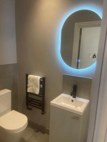 Un baño con inodoro y lavabo con luz azul. en Luxury en-suite in modern house, en Catford