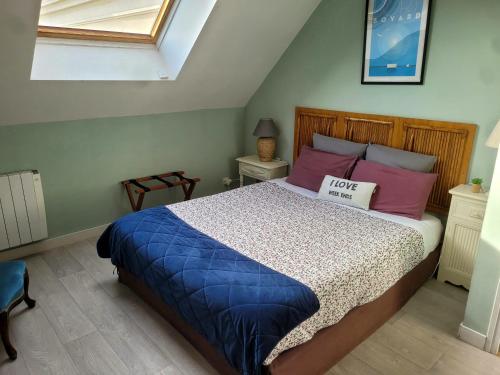 a bedroom with a bed with blue and pink pillows at La Roseraie in Neuville-de-Poitou