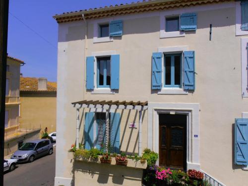 a house with blue shutters and flowers on a street at L'Orchidée in Ginestas