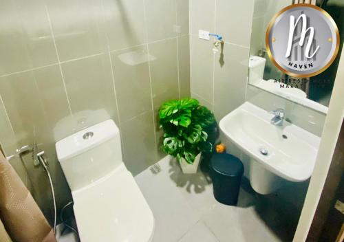 een badkamer met een toilet, een wastafel en een plant bij M Haven in Manilla