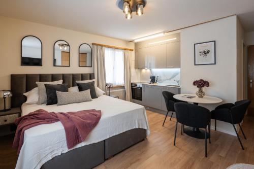 a bedroom with a bed and a table and a kitchen at Chalet Alberti Davos Platz in Davos
