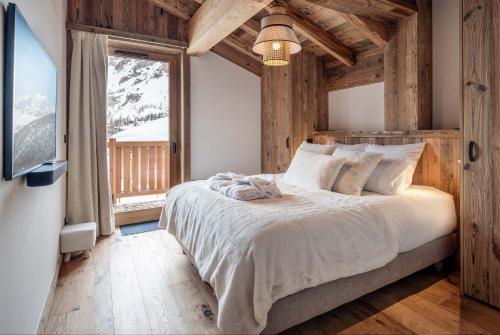 a bedroom with a bed and a large window at Madame Vacances Chalet Arda in Le Joseray