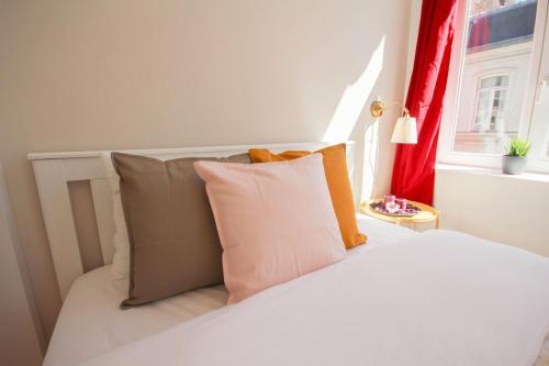 een slaapkamer met een wit bed met kussens en een raam bij Lille centre- Nice and bright equipped studio in Lille