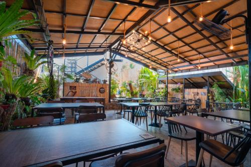 um restaurante com mesas, cadeiras e plantas em Bay Area Lodge em Coron