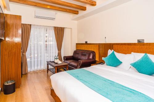 a bedroom with a large bed and a chair at Pokhara Alpine and Springs in Pokhara