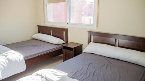 a bedroom with two beds and a window at Airport Apartment M&A in Nador