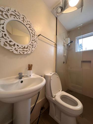 a bathroom with a sink and a toilet and a mirror at CasaDel Beach House in Mabini