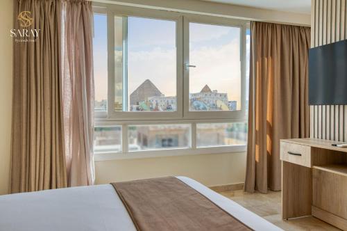 a bedroom with a bed and a large window at Saray Pyramids & Museum View Hotel in Cairo