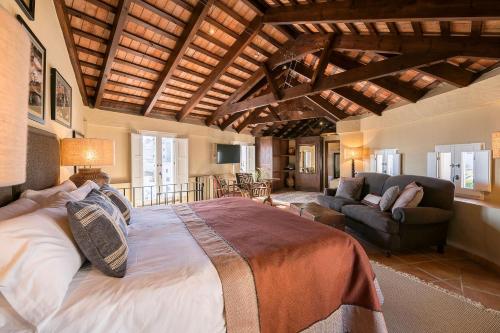 a bedroom with a large bed and a living room at Hotel La Casa del Califa in Vejer de la Frontera