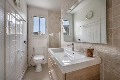 ein weißes Bad mit einem Waschbecken und einem WC in der Unterkunft Sejour avec Hoomy au Pouliguen in Le Pouliguen