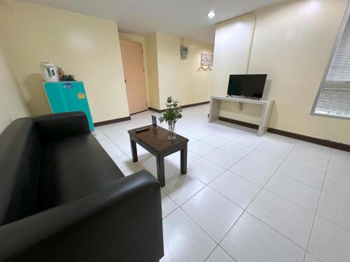 a living room with a couch and a table and a tv at Aryan Suites Hotel in Bangkok