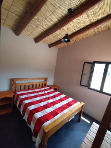 a bedroom with a bed with a red and white blanket at CABAÑAS RIVIERA in Huacalera