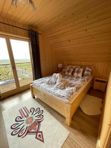 a bed in a wooden room with a large window at Domek pod lasem in Klikuszowa