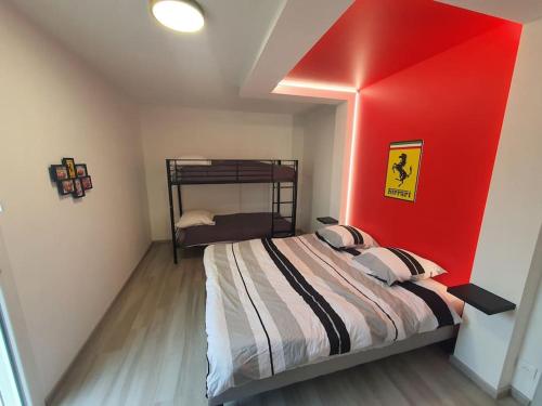 een slaapkamer met een bed met een rode muur bij Maison à thème le Mans 66 in Guécélard