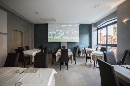 a dining room with tables and chairs and a screen at Hotel Astoria in Fidenza