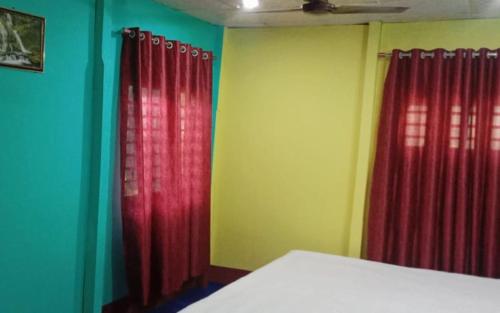 a room with red curtains and green walls at Leo Jungle Retreat by StayApart , Jaldapara in Mādāri Hāt