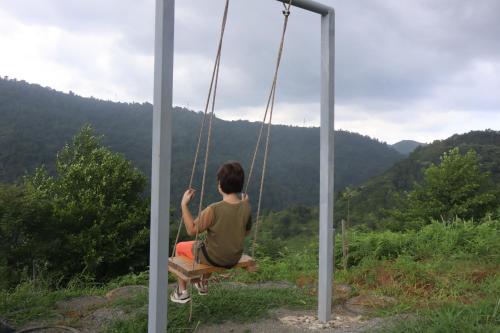 a woman sitting on a swing looking out at the mountains at Breathe Inn in Batumi