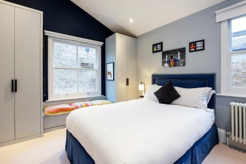 a bedroom with a large bed and two windows at Veeve - A Vision in Blue in London