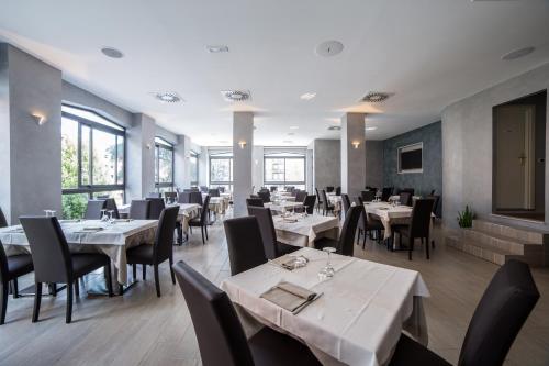 a restaurant with white tables and chairs and windows at Hotel Astoria in Fidenza