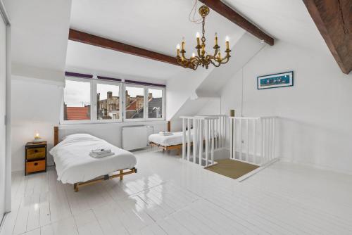 a white bedroom with two beds and a chandelier at Karaktervolle en ruime woning aan zee voor 10p in Ostend