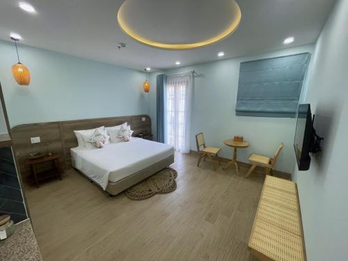 a bedroom with a bed and a television and a table at Aurora Phu Quoc Hotel & Golf 3D in Phu Quoc