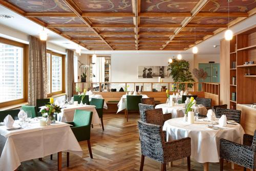 un comedor con mesas y sillas blancas en Genießer - & Romantik Hotel DAS SCHIFF en Hittisau