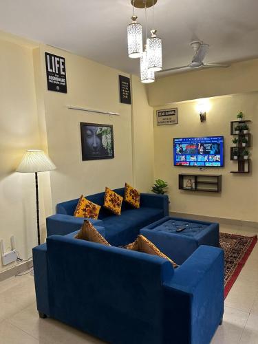 a blue couch in a living room with a tv at Royal Ambience in Ghaziabad
