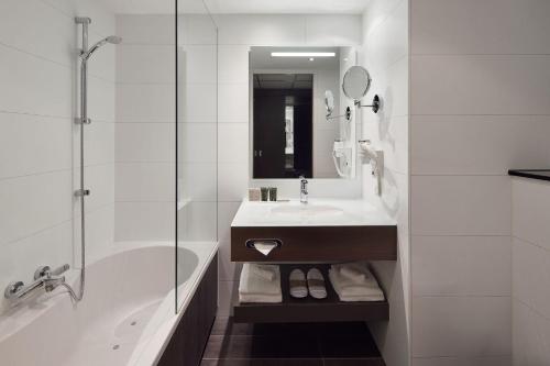 y baño con bañera, lavamanos y ducha. en Van der Valk Hotel Amersfoort-A1 en Amersfoort