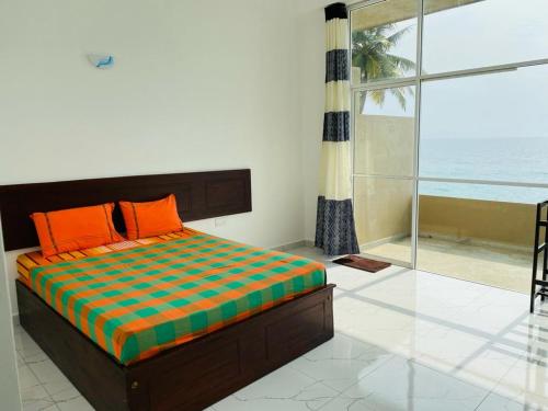 ein Schlafzimmer mit einem Bett mit orangefarbenen Kissen und einem Fenster in der Unterkunft Sevenra Grand Beach Hotel in Ambalangoda