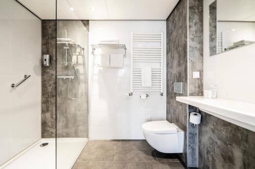 a bathroom with a shower and a toilet and a sink at Hotel Hulst in Hulst
