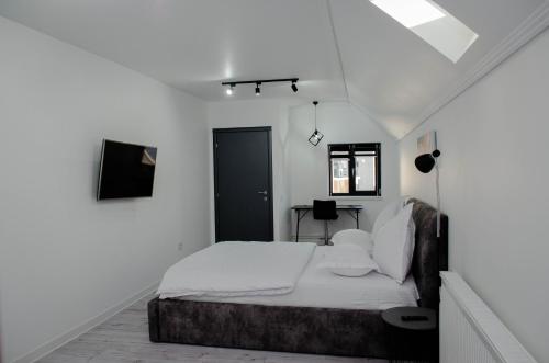 a white bedroom with a bed and a black door at PentGarden penthouse jacuzzi in Târgu Jiu