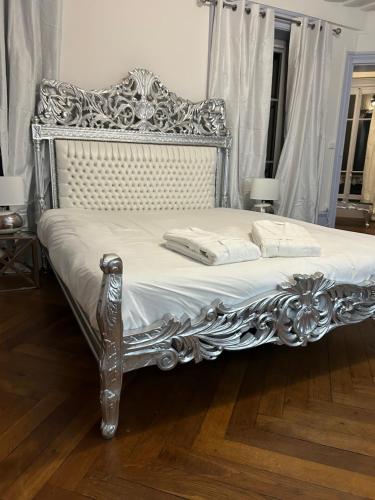 ein silbernes Bett mit weißer Bettwäsche und Kissen darauf in der Unterkunft Château Le Fournel in La Fouillouse