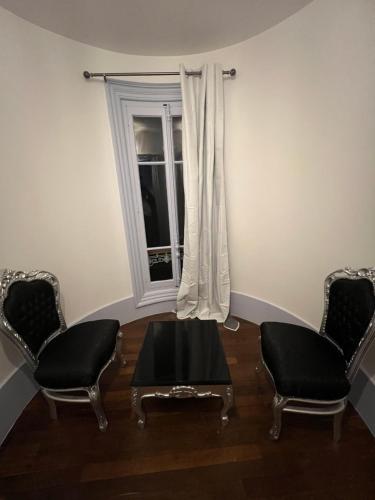 sala de estar con 2 sillas, mesa y ventana en Château Le Fournel, en La Fouillouse