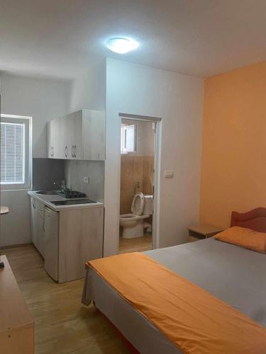 a bedroom with a bed and a bathroom with a toilet at Vasiljević apartmani in Igalo
