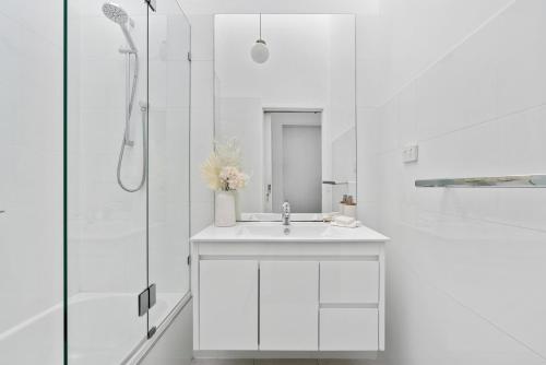 a white bathroom with a sink and a shower at Stunning water views - Bayside Beach House Mornington in Mornington