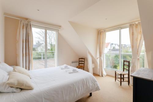 une chambre avec un lit blanc et une grande fenêtre dans l'établissement La Camillette - 5 chambres à 10min de la plage, à Pléneuf-Val-André