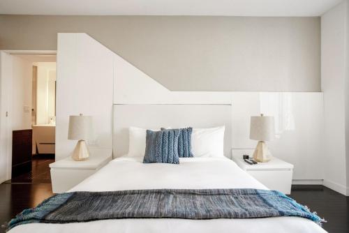 a bedroom with a large white bed with two lamps at Blueground Tribeca lounge nr WTC NYC-1375 in New York