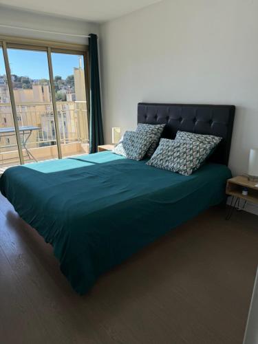 une chambre avec un grand lit avec une grande fenêtre dans l'établissement Modern 60m2 apartment with 2 balconies, at 50 meters from sea, à Antibes