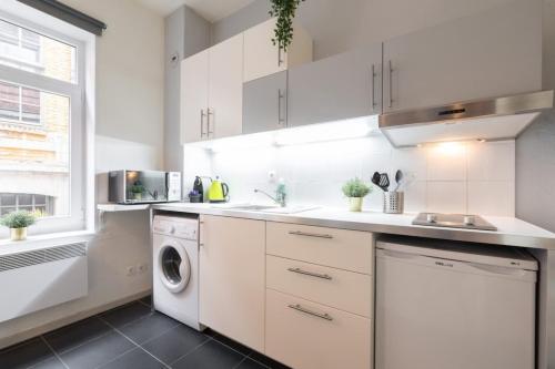 une cuisine avec des armoires blanches et une laveuse et une sécheuse dans l'établissement Vieux Lille bright duplex ! 3pers, à Lille