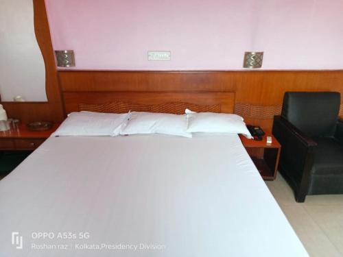 a bed in a hotel room with a chair and a bed sidx sidx at HOTEL HEERA in Kolkata