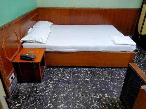 a bed with a wooden frame and a table with a white sheets at HOTEL HEERA in Kolkata