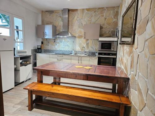 - une cuisine avec une table en bois et un mur en pierre dans l'établissement Appartement/gîte Amets, à Sare