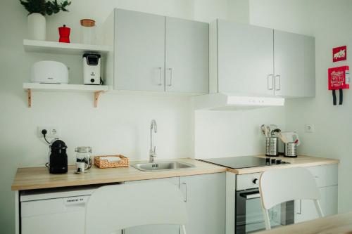 a kitchen with white cabinets and a sink at Belém Tejo - Memória by Local in Lisbon