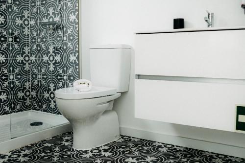 a white bathroom with a toilet and a shower at Belém Tejo - Memória by Local in Lisbon
