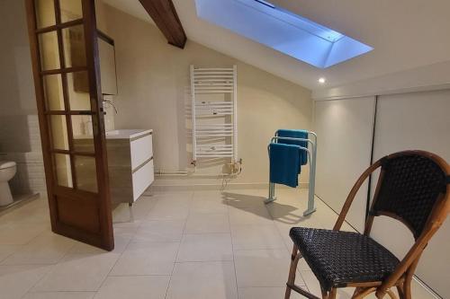 uma casa de banho com um lavatório e uma cadeira num quarto em La rose des vents - proche Paris em Argenteuil